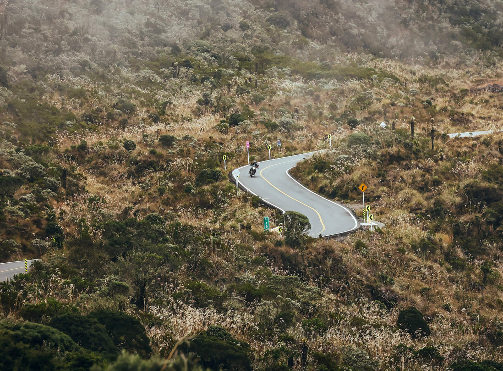 One motorcycle rider on a RE Himalayan 450 riding though the Andes in Colombia on a paved road during an adventure with Fire of The South