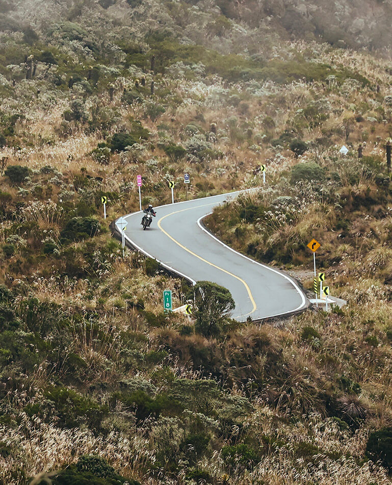 One motorcycle rider on a RE Himalayan 450 riding though the Andes in Colombia on a paved road during an adventure with Fire of The South